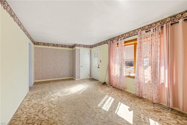 empty room with visible vents, wallpapered walls, and baseboards