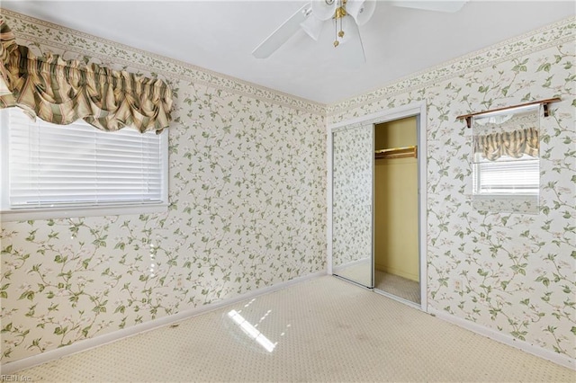 unfurnished bedroom featuring a ceiling fan, baseboards, carpet floors, wallpapered walls, and a closet