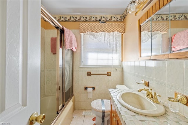 full bath featuring toilet, tile walls, tile patterned flooring, bath / shower combo with glass door, and vanity