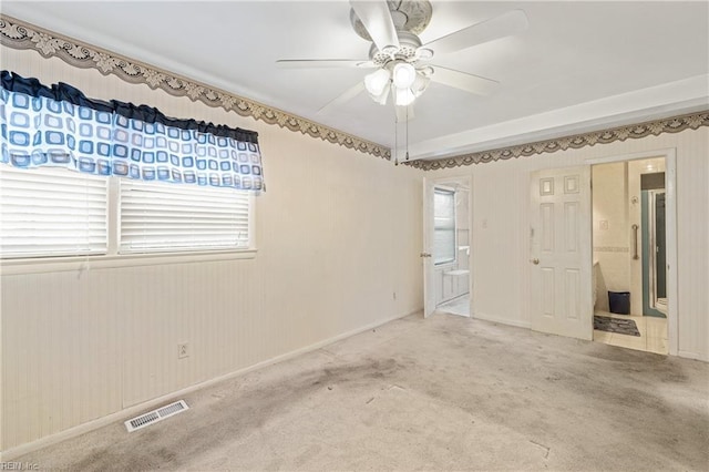 carpeted spare room with visible vents and a ceiling fan