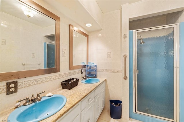 bathroom with double vanity, a shower stall, tile walls, and a sink