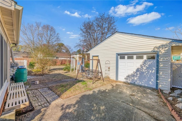 detached garage featuring driveway and fence