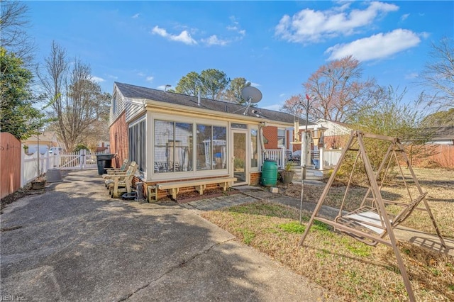 rear view of property with a sunroom, fence, and a gate