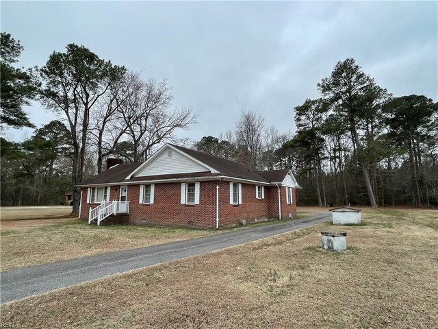 view of side of home with driveway, a chimney, crawl space, a lawn, and brick siding