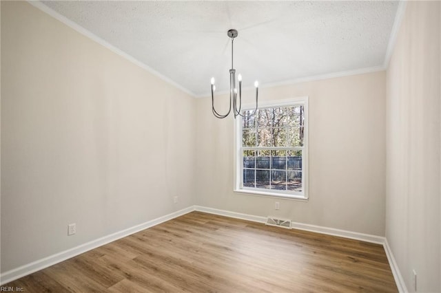 unfurnished dining area with wood finished floors, baseboards, ornamental molding, a textured ceiling, and a notable chandelier