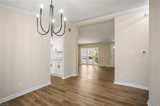 unfurnished dining area with dark wood finished floors, an inviting chandelier, crown molding, and baseboards