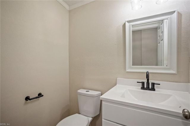 bathroom featuring toilet, vanity, and a textured wall