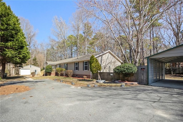 view of front of home featuring aphalt driveway, an outbuilding, fence, and crawl space