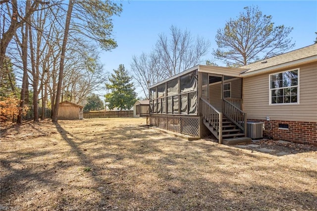 view of yard with an outbuilding, fence, central AC, a sunroom, and a storage shed