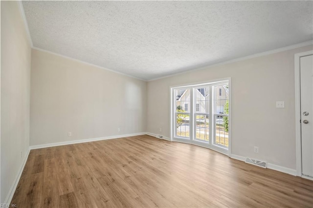 empty room with crown molding, light wood-style floors, visible vents, and a textured ceiling