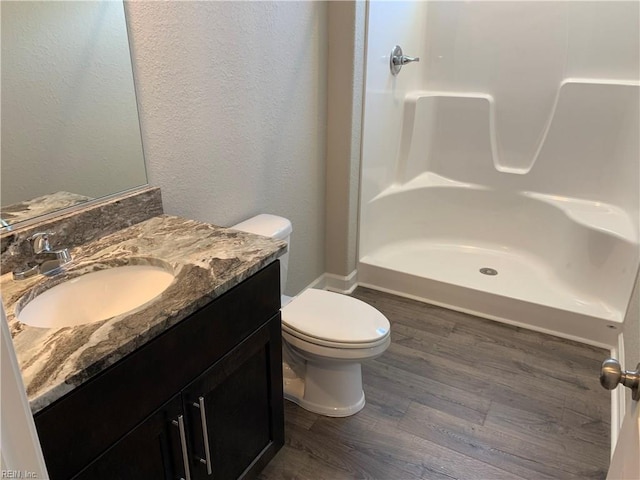 bathroom with toilet, walk in shower, wood finished floors, and vanity