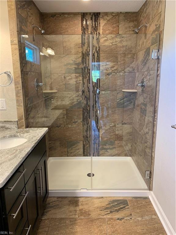 full bathroom with vanity, a shower stall, and baseboards