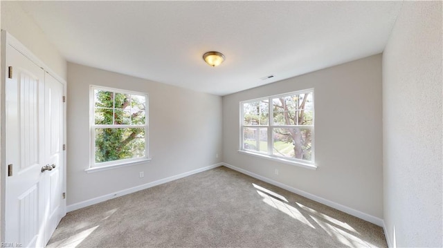 empty room with visible vents, baseboards, and carpet flooring