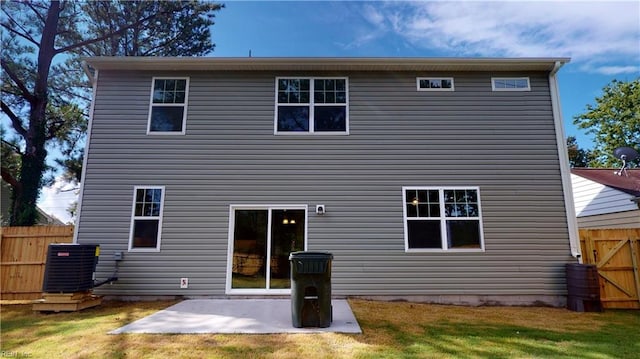 rear view of property featuring a patio, central air condition unit, fence, and a lawn