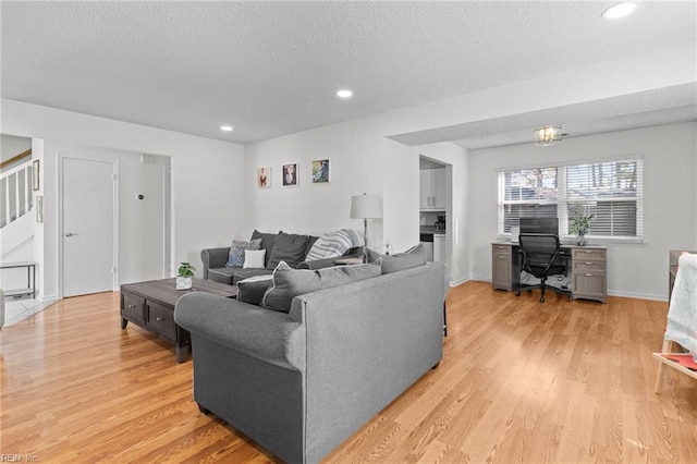 living area featuring stairway, recessed lighting, a textured ceiling, and light wood-style floors