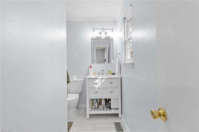 half bath with visible vents, toilet, crown molding, baseboards, and vanity