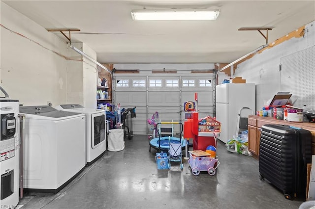 garage featuring washing machine and clothes dryer, water heater, and freestanding refrigerator