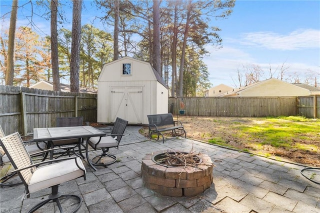 view of patio / terrace with an outdoor structure, a fenced backyard, an outdoor fire pit, and a shed