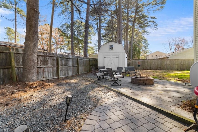 view of patio featuring an outbuilding, a fire pit, a fenced backyard, and a shed