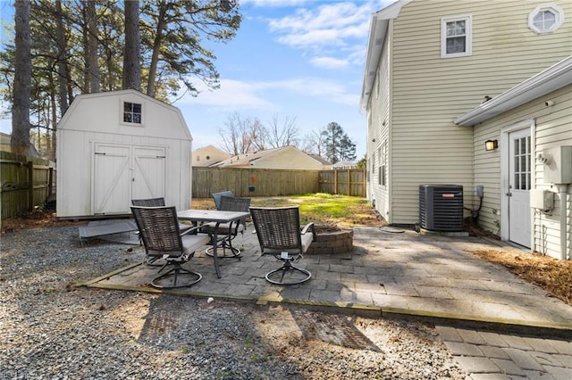 view of patio featuring a storage unit, central air condition unit, a fire pit, and a fenced backyard