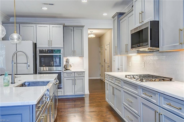 kitchen featuring light countertops, ornamental molding, gray cabinets, appliances with stainless steel finishes, and dark wood-style floors