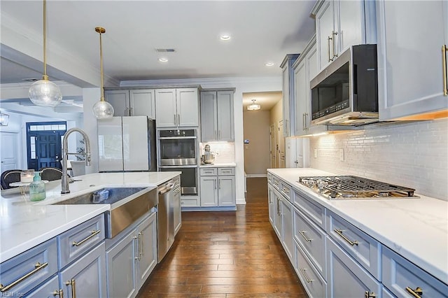 kitchen with dark wood finished floors, gray cabinetry, ornamental molding, stainless steel appliances, and decorative light fixtures