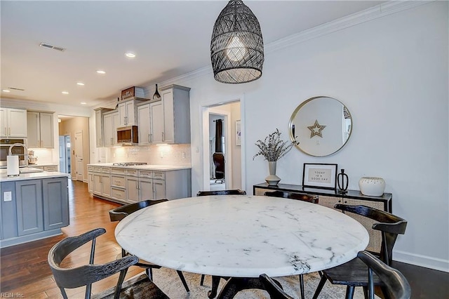 dining room featuring visible vents, ornamental molding, recessed lighting, baseboards, and dark wood-style flooring