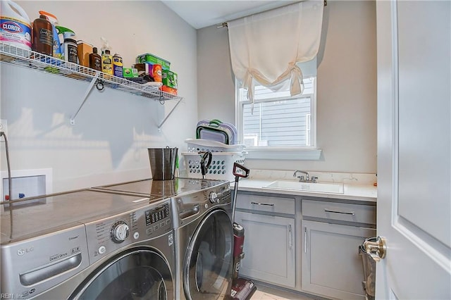 clothes washing area featuring washing machine and clothes dryer, cabinet space, and a sink