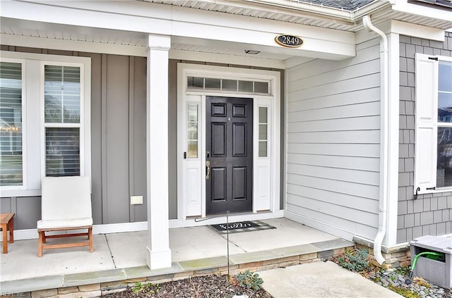 doorway to property with board and batten siding and a porch