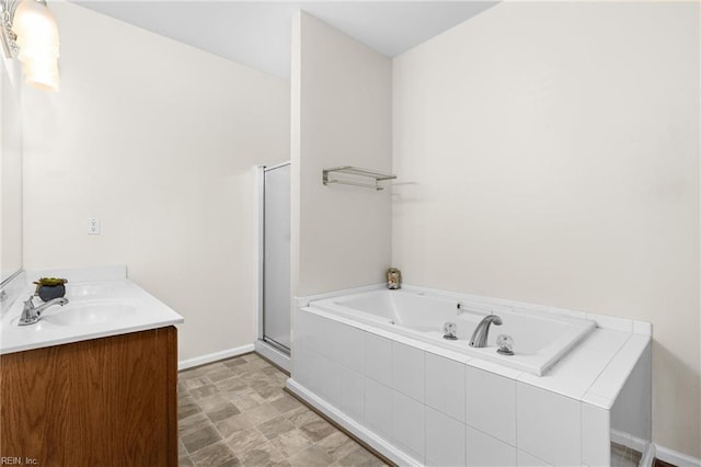 bathroom with a bath, a stall shower, vanity, and baseboards