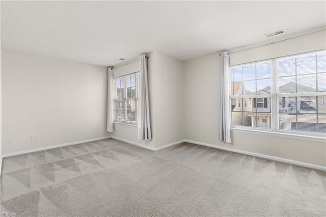 carpeted spare room with visible vents and baseboards