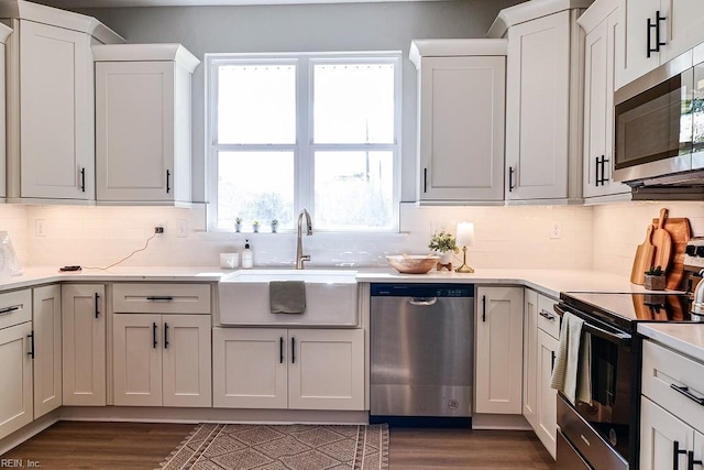 kitchen featuring dark wood finished floors, light countertops, appliances with stainless steel finishes, and a sink