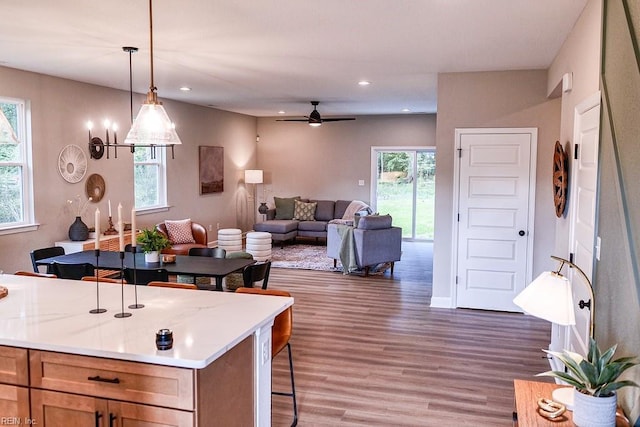 kitchen with decorative light fixtures, open floor plan, a kitchen bar, recessed lighting, and wood finished floors