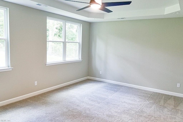 spare room with visible vents, baseboards, a raised ceiling, and carpet