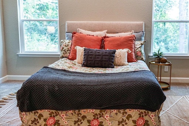 carpeted bedroom featuring multiple windows and baseboards