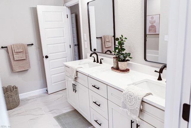 full bathroom featuring a sink, baseboards, marble finish floor, and double vanity