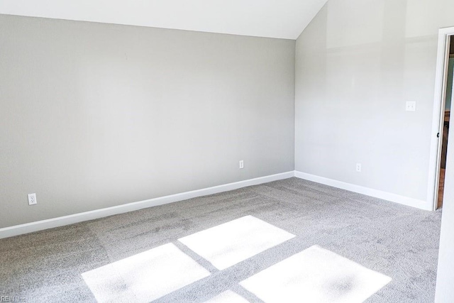 unfurnished room featuring carpet, lofted ceiling, and baseboards