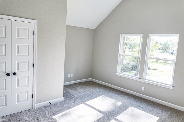 unfurnished bedroom with baseboards, carpet floors, a closet, and vaulted ceiling