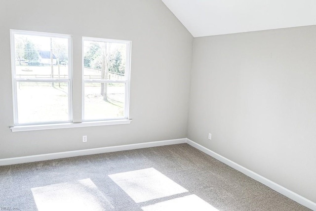 empty room featuring lofted ceiling, a healthy amount of sunlight, baseboards, and carpet floors