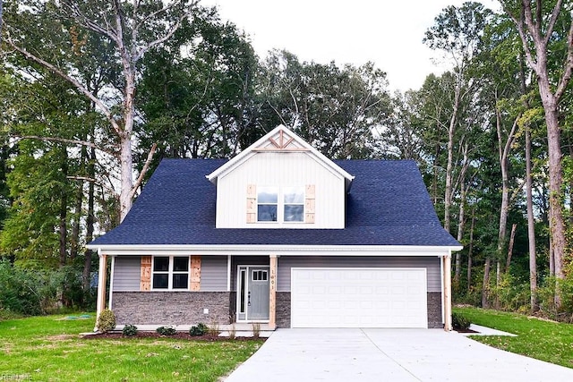 view of front of house with a front yard, concrete driveway, a garage, and a shingled roof