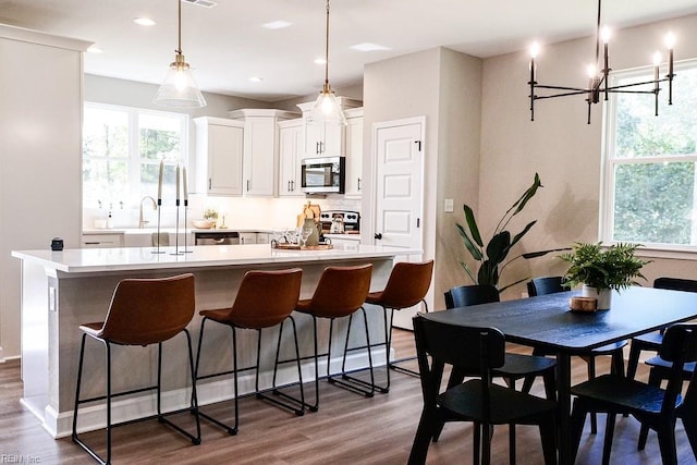 kitchen with stainless steel appliances, dark wood-type flooring, a center island with sink, and white cabinetry