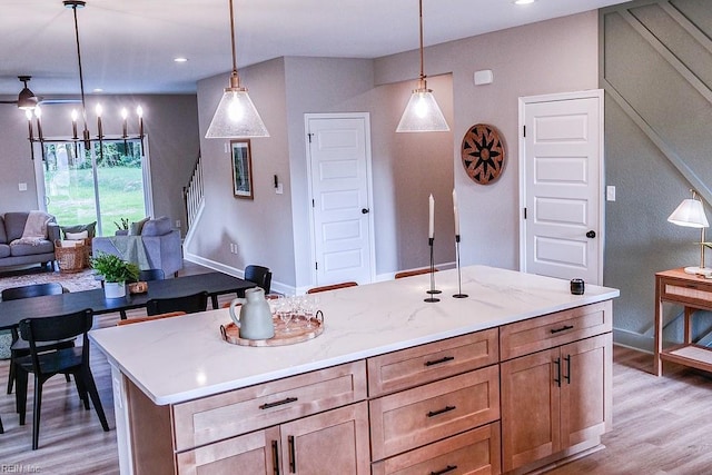 kitchen featuring ceiling fan, light wood-style flooring, open floor plan, and pendant lighting