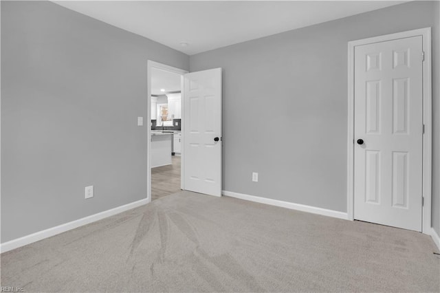 unfurnished bedroom featuring light colored carpet and baseboards