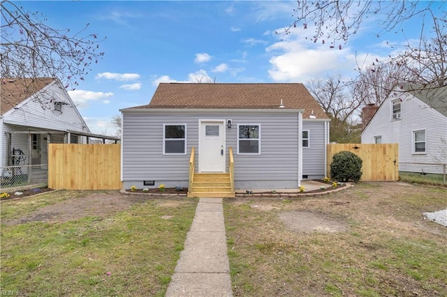 bungalow with a front lawn, entry steps, fence, a shingled roof, and crawl space