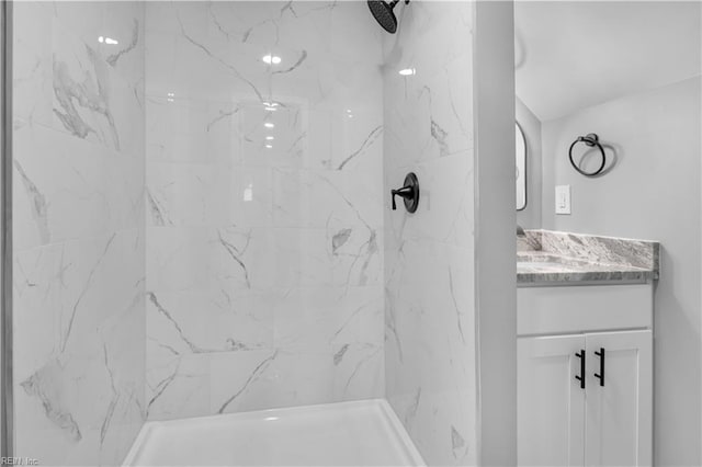 bathroom with vanity and a marble finish shower