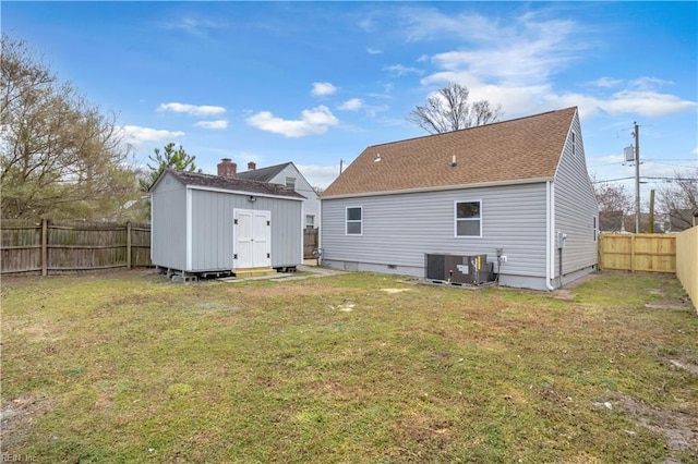 rear view of property featuring a shed, a yard, a fenced backyard, an outdoor structure, and central air condition unit