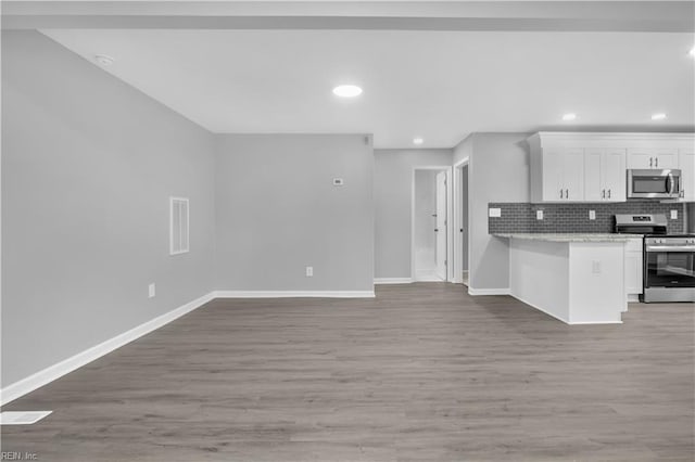 kitchen with tasteful backsplash, white cabinetry, stainless steel appliances, light wood-style floors, and baseboards