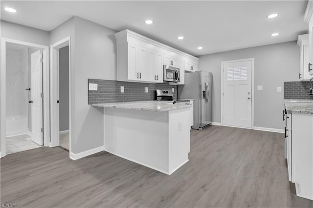 kitchen with white cabinetry, light stone counters, light wood-type flooring, and appliances with stainless steel finishes