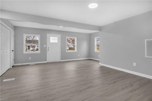 unfurnished living room featuring visible vents, baseboards, and dark wood-style flooring