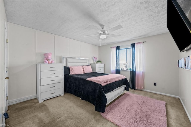 bedroom featuring baseboards, light carpet, a textured ceiling, and ceiling fan